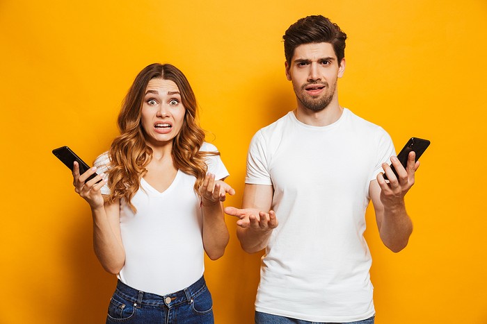 Confused Couple Holding Phones