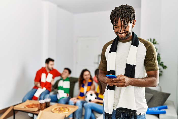Smiling Man on Phone With Football Friends