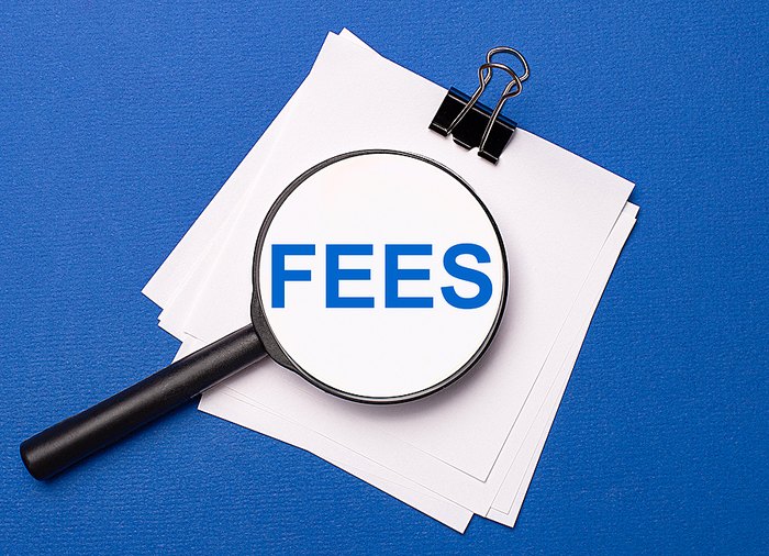 Fees Text Under Magnifying Glass on Blue Background