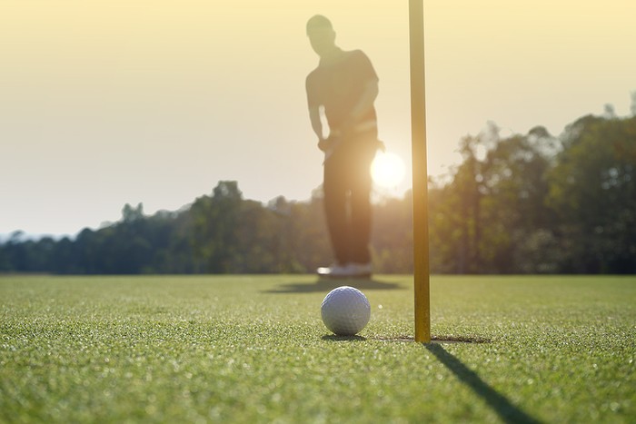 Blurred Golfer Putting at Sunset