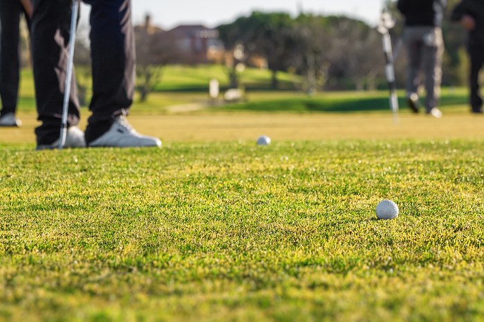 Blurred Legs of Golfers Around Green