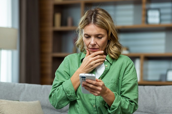 Worried Woman Sitting Holding Smartphone