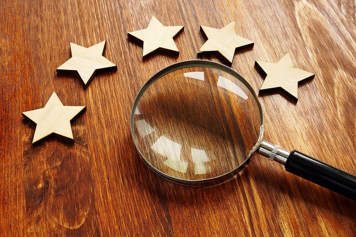 Five Stars and Magnifying Glass on Wooden Desk
