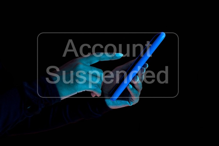 Woman Holding Phone Against Dark Background with Account Suspended Message
